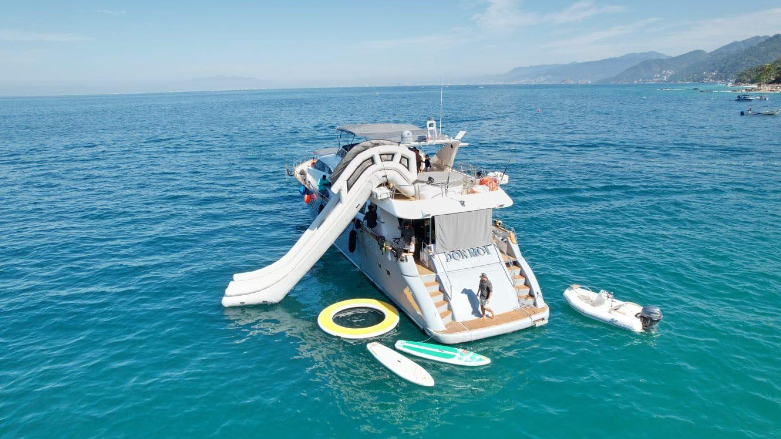 Guests on the waterslide of the 85 ft Azimut yacht anchored off Puerto Vallarta, an owner-listed luxury charter