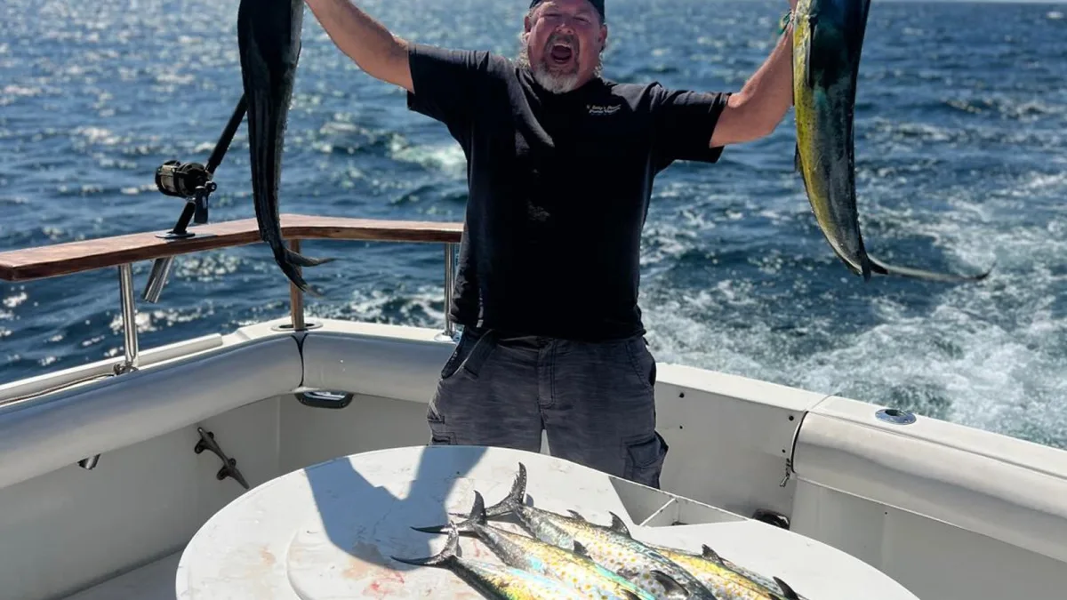 A fisherman lifting two dorado aboard a Puerto Vallarta sportfishing charter